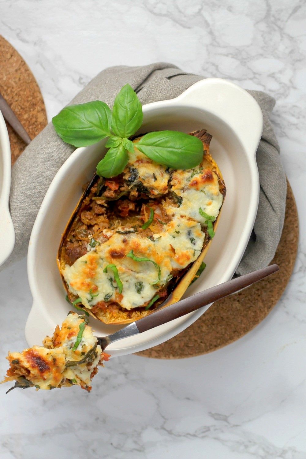 Spaghetti squash lasagna boats with a fork taking a bite.