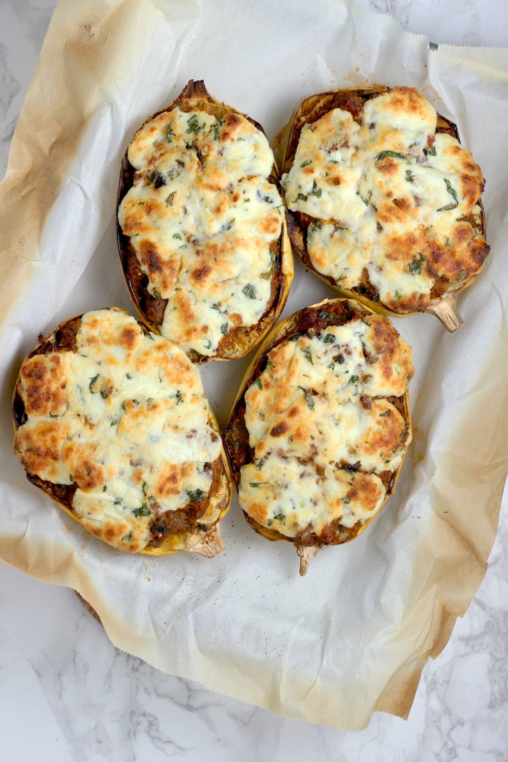 Lasagna with spaghetti squash in four cooked spaghetti squash halves with melted cheese.