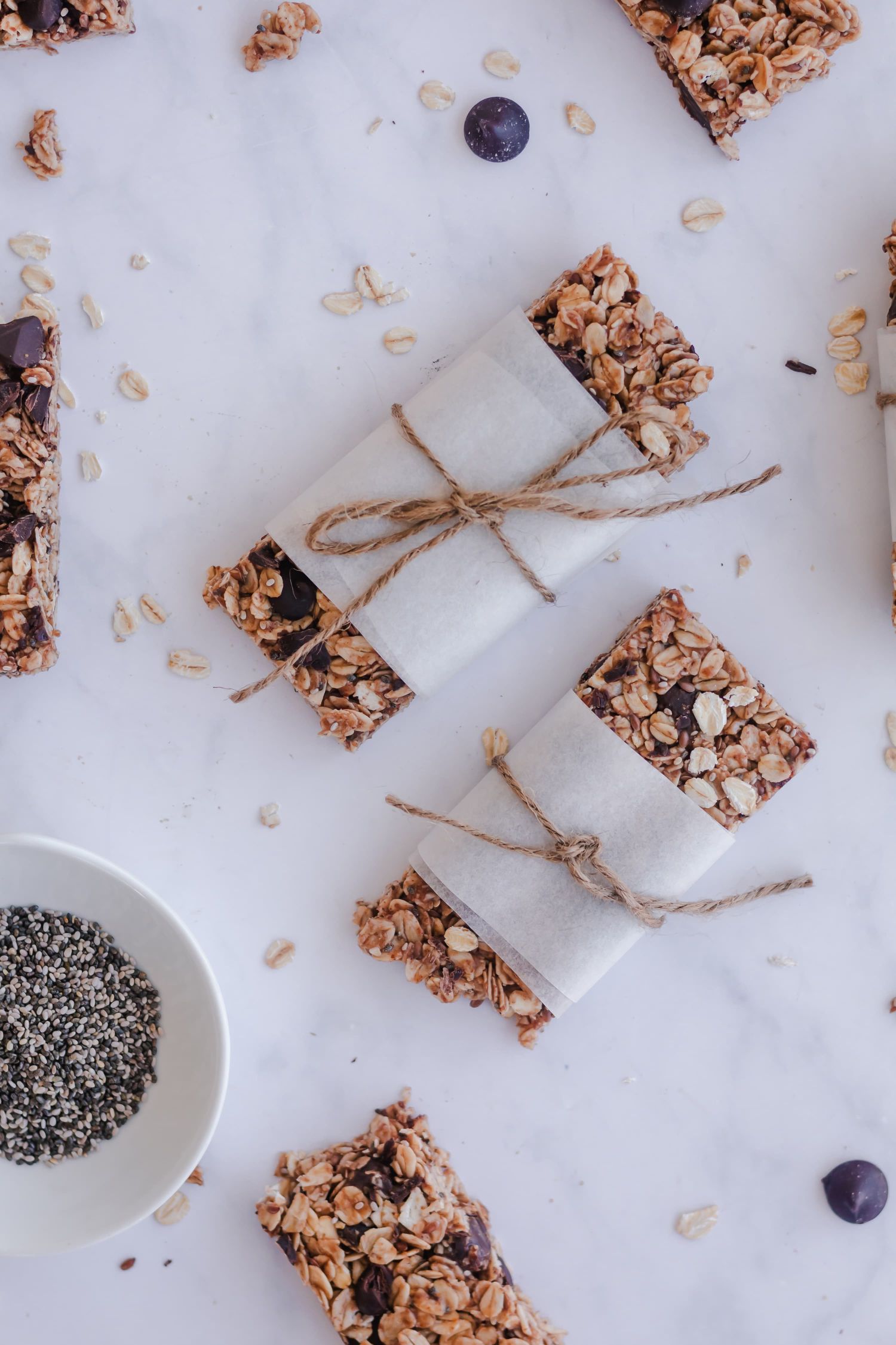 Oat granola bars made with honey and almond butter with chocolate chips wrapped in parchment paper.