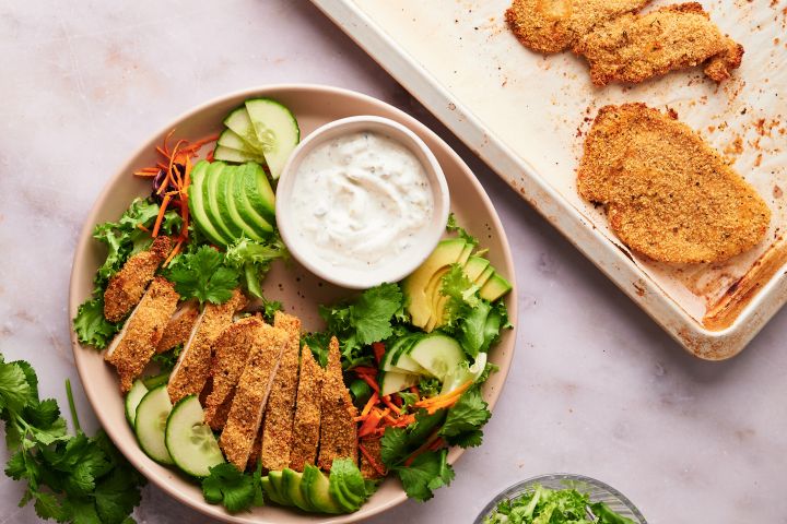 Simple Baked Chicken Cutlets Baked chicken cutlets on a plate with salad and ranch dressing.