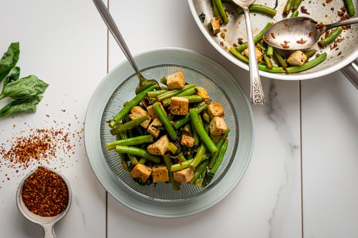 Basil Tofu with Green Beans Basil tofu with green beans in a glass bowl with a skillet on the side.