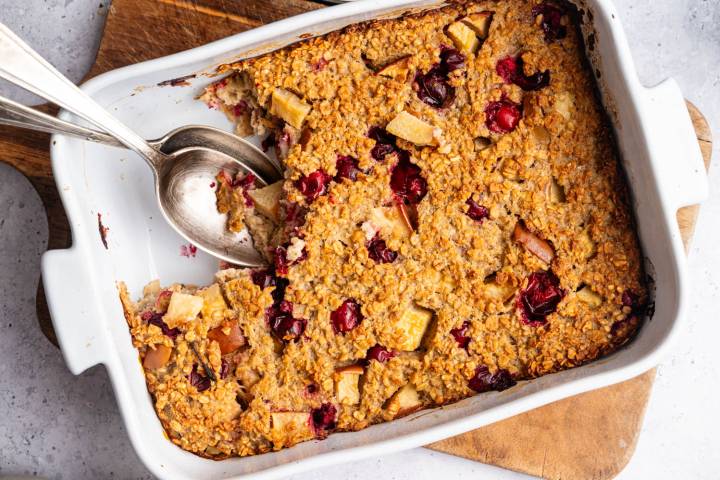 Cranberry Apple Baked Oatmeal Golden-baked oatmeal casserole with cranberry and apple chunks in a white dish.