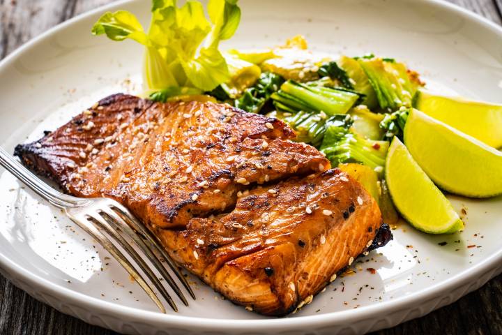 Hoisin Asian Salmon Hoisin salmon with caramelized edges on a plate with bok choy and limes.