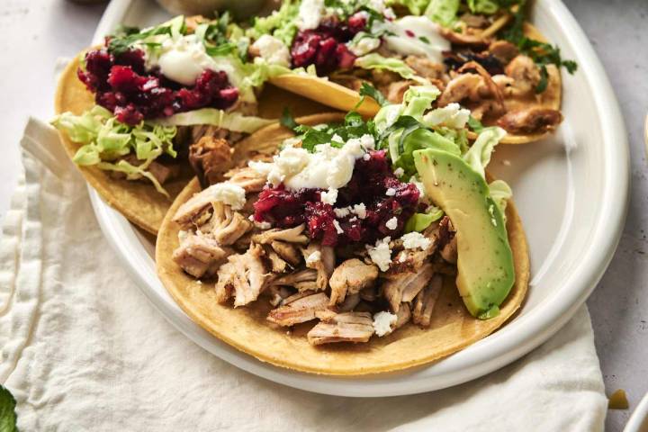 Leftover Turkey Tacos Leftover turkey tacos with cranberry relish, cilantro, avocado, and queso fresco being served on a plate.