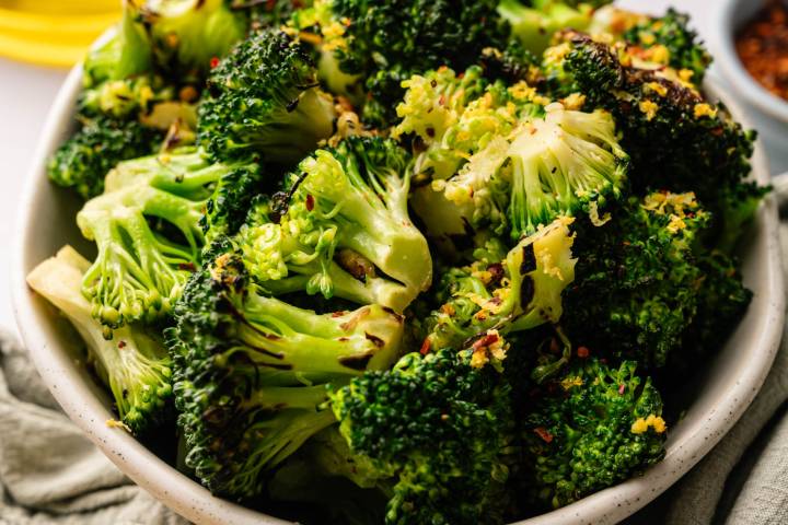 Sauteed Broccoli A bowl of roasted broccoli florets garnished with lemon zest and chili flakes.