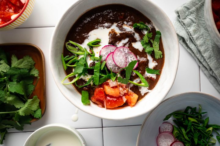 Slow Cooker Black Bean Soup Slow cooker Black Bean Soup in a bowl with sour cream, cilantro, tomatoes, and radishes.
