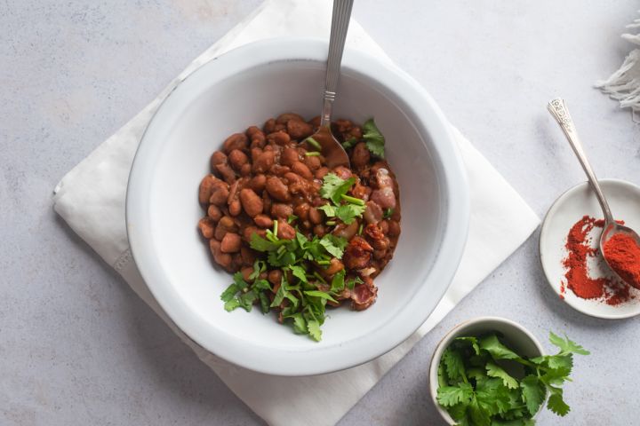 Slow Cooker Borracho Beans Slow cooker borracho beans in a bowl with cilantro, crispy bacon, and beer broth.