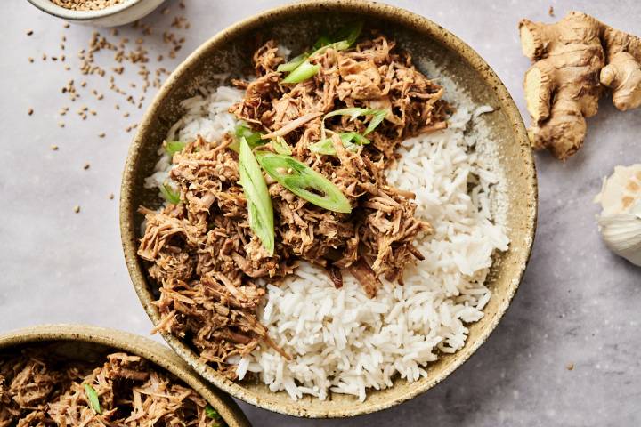 Slow Cooker Sesame Beef Shredded sesame beef over rice with green onion garnish.