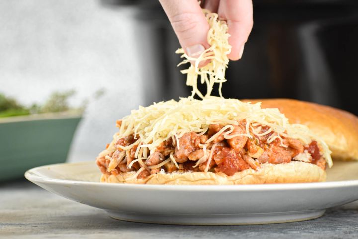 Slow Cooker Tuscan Turkey Sloppy Joes Slow cooker Tuscan turkey sloppy joes on a roll with shredded cheese.