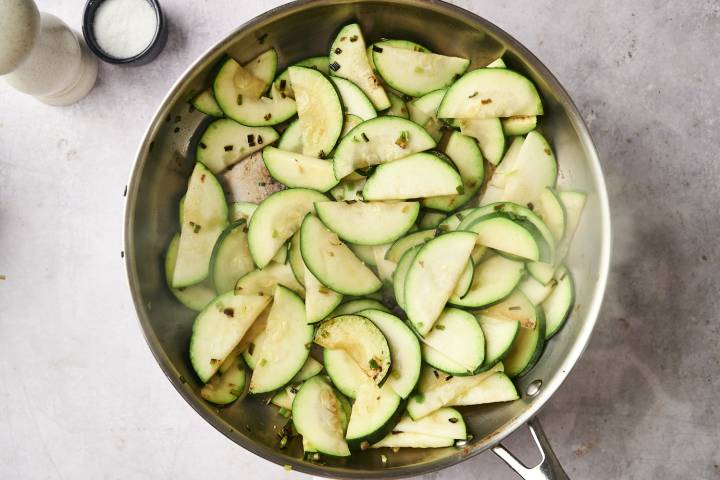 Ground Turkey and Zucchini Stir Fry Sliced zucchini cooking in a stainless steel skillet, lightly sautéed with garlic and seasonings.