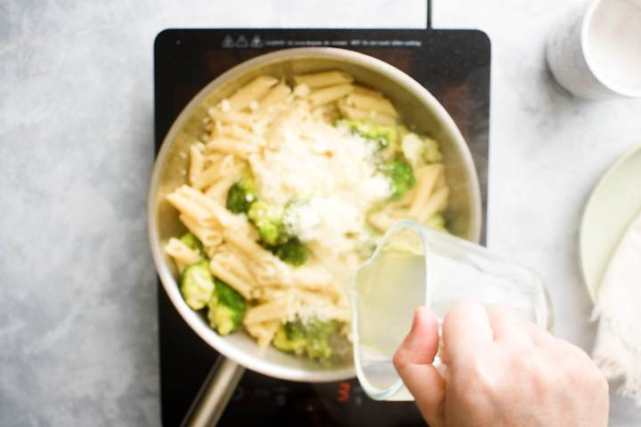 Lemon Broccoli Pasta Pasta cooknig water being added to a pan of pasta, broccoli, and lemon.