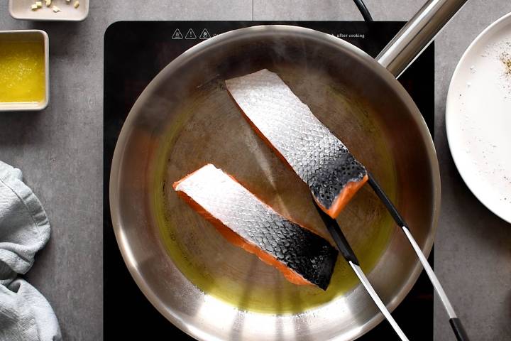 Pan Seared Salmon Salmon cooking with the flesh side down in a pan.