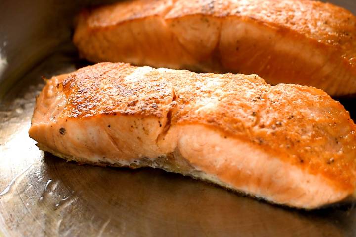 Pan Seared Salmon Salmon being seared in a pan with the skin side down.