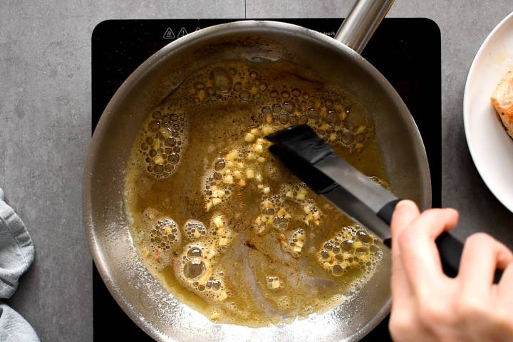 Pan Seared Salmon Butter and garlic cooking in a pan with tongs.