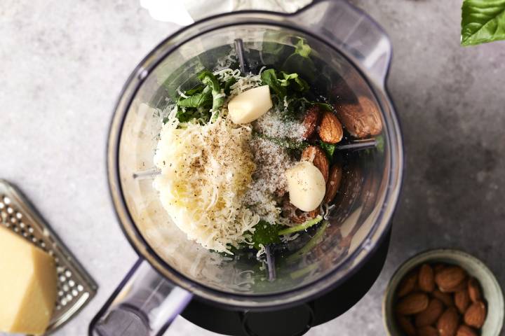 Pesto Chicken A blender filled with fresh basil, garlic cloves, almonds, grated Parmesan, and black pepper, the start of a homemade pesto sauce.
