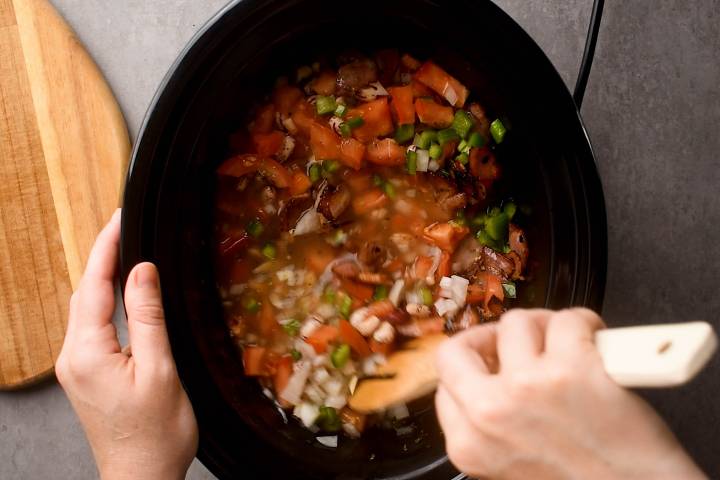 Slow Cooker Charro Beans (Frijoles Charros) Pinto beans with vegetables, broth, and spices being stirred in a slow cooker.