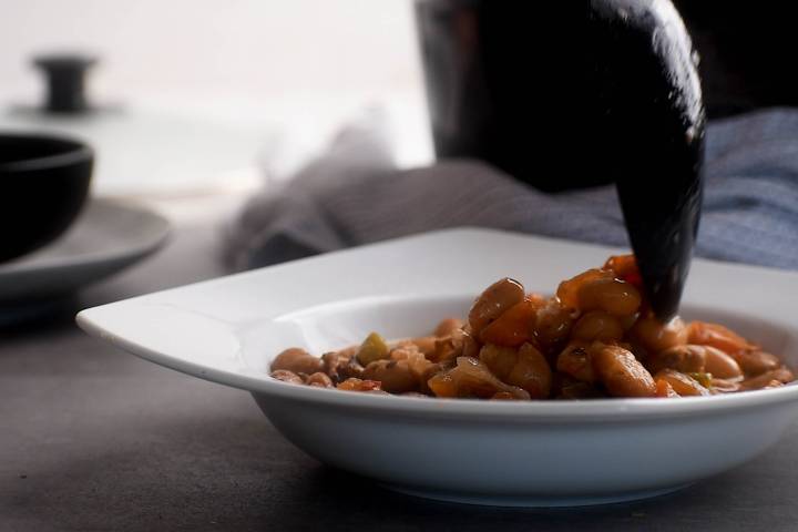 Slow Cooker Charro Beans (Frijoles Charros) Charro beans being served in a bowl with a spoon.