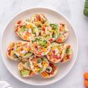 The Best Healthy Party Snacks and Appetizers Healthy cream cheese pinwheels with vegetables served on a white plate/