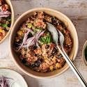 Mexican Quinoa (Slow Cooker, Instant Pot, or Stovetop) Bowls of cooked Mexican quinoa topped with fresh red onion slices and chopped cilantro, ready to be served with additional toppings on the side.