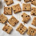 No Bake Peanut Butter Banana Oat Bars No Bake Oatmeal bars with chocolate chips, chia seeds, flaxseed, and coconut on parchment paper.