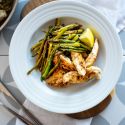 One Pan Lemon Garlic Chicken and Asparagus One pan lemon garlic chicken and asparagus served with fresh lemons in a bowl and in a skillet.