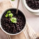 Slow Cooker Black Beans Slow cooker black beans served in two bowls with cilantro and a spoon.