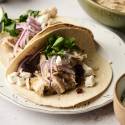 Slow Cooker Turkey Tacos Shredded turkey tacos with red onion, cilantro, dried cranberries, and crumbled cheese on soft flour tortillas.