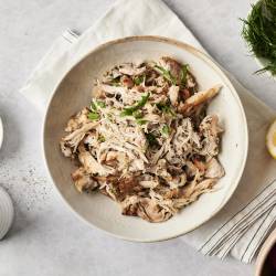 Easy Greek Chicken (Instant Pot, Slow Cooker, or Stovetop) A bowl of shredded Greek chicken, garnished with fresh herbs. Surrounded by lemon, dill, cherry tomatoes, and salt, creating a fresh Mediterranean feel.