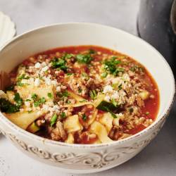 Healthy Slow Cooker Lasagna Soup A bowl of lasagna soup with a rich tomato broth, ground meat, zucchini, and lasagna noodles, topped with parmesan cheese and fresh parsley.