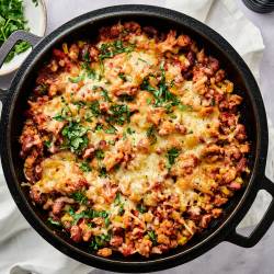 Healthy Taco Casserole Taco casserole with pinto beans, onions, peppers, turkey, corn, salsa, and melted cheese with chips, cilantro, and jalapeno on the side.