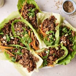 Korean Beef Lettuce Wraps A top-down shot of a plate of Korean beef lettuce wraps and a side of shredded carrots.