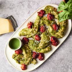 Pesto Chicken Juicy pesto chicken tenders topped with roasted cherry tomatoes and Parmesan cheese, served with extra pesto sauce on the side.