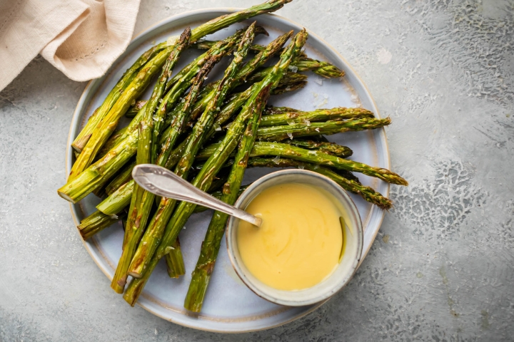 Easy and Delicious Asparagus Recipes Roasted asparagus on a plate with hollandaise sauce.