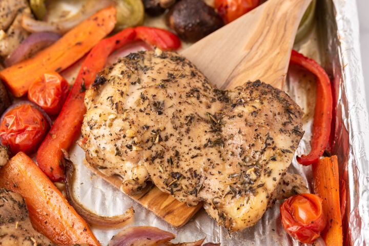 30+ Easy Chicken Thigh Recipes Roasted chicken thigh on a wooden spatula with vegetables.