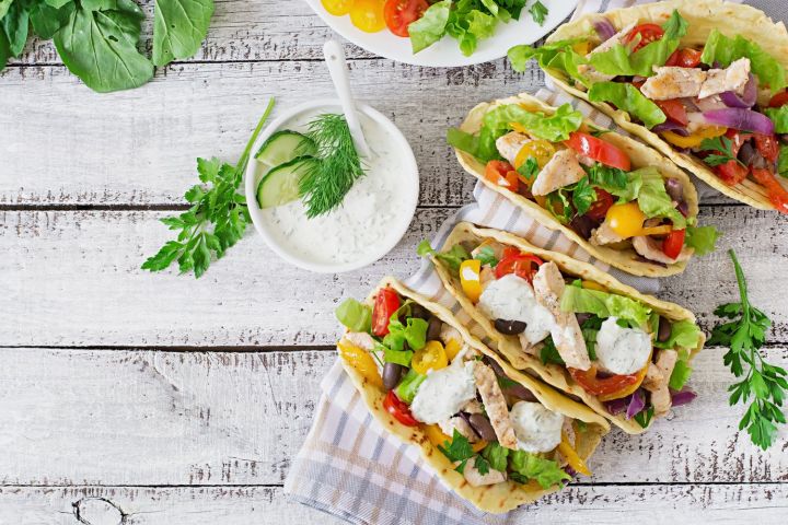 12 Ways to Use Leftovers in Your Weekly Meal Plan Chicken tacos with fresh vegetables on a gray cutting board for leftovers.