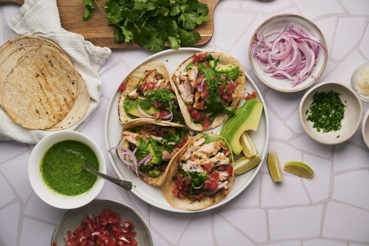 Over 50 Delicious Mexican Recipes Mexican chicken tacos with tomatoes, onions, tortillas, salsa, and cilantro.