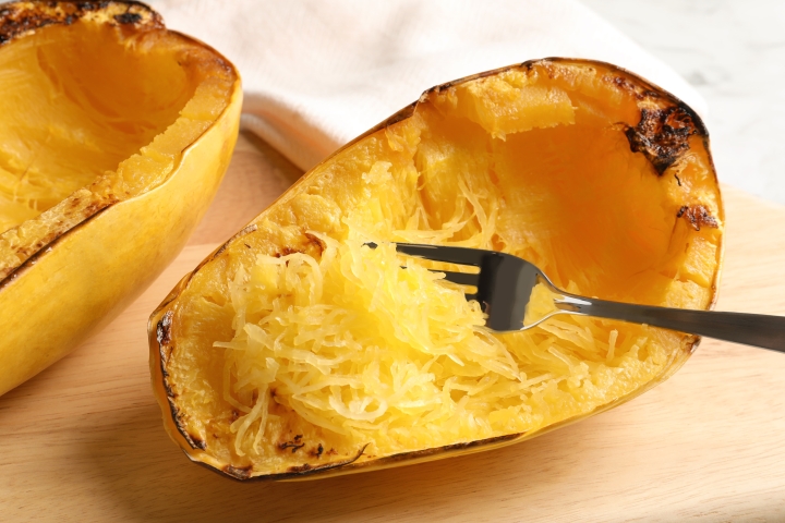 How to Cook Spaghetti Squash (5 Ways!) Roasted spaghetti squash on a cutting board with a fork scraping the squash into strands.