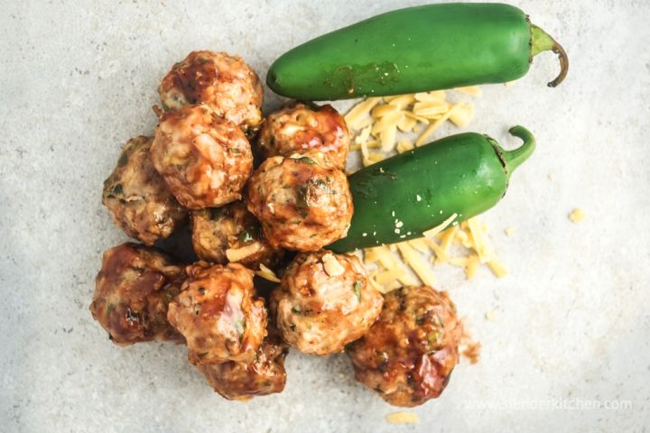 BBQ Cheddar Jalapeno Chicken Meatballs Barbecue cheddar meatballs on a cutting board with fresh jalapenos on the side.