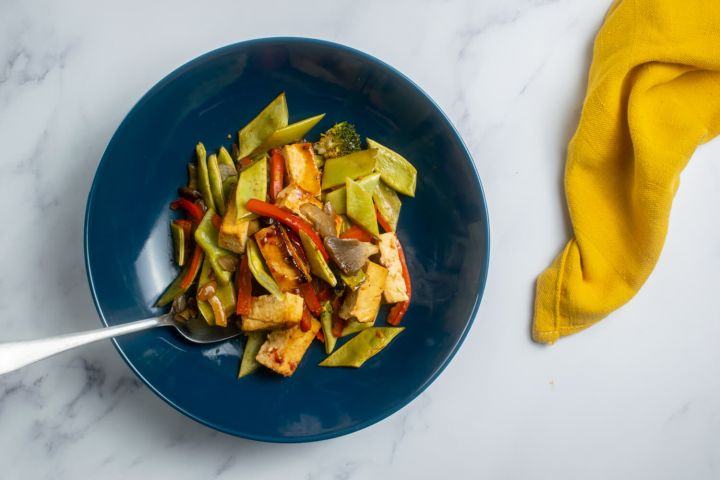 Sheet Pan Asian Tofu and Vegetable Stir Fry Sheet pan asian tofu with vegetables in a blue bowl with a yellow napkin.