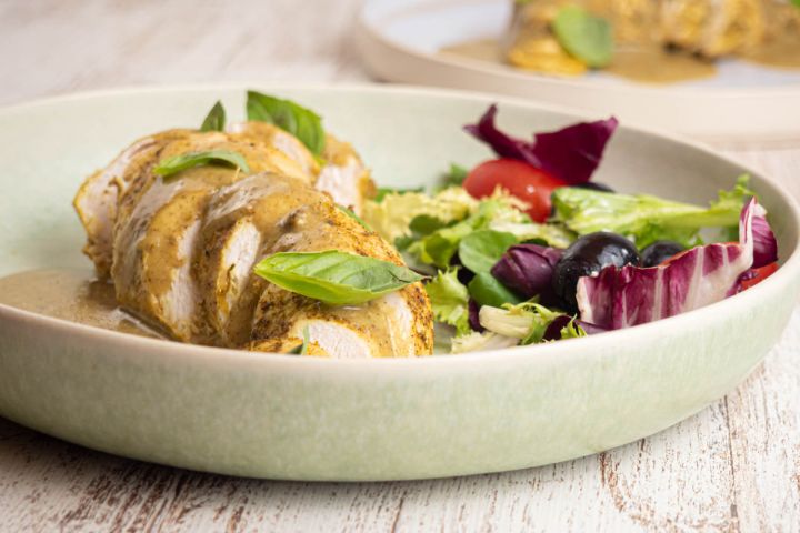 Slow Cooker Coconut Basil Chicken Slow cooker coconut basil chicken on a plate with creamy sauce and salad on the side.