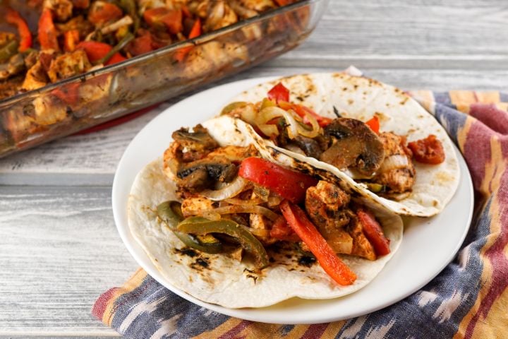 Baked Chicken Fajitas Baked chicken fajitas served in flour tortillas with chicken breast, bell peppers, and red onions.