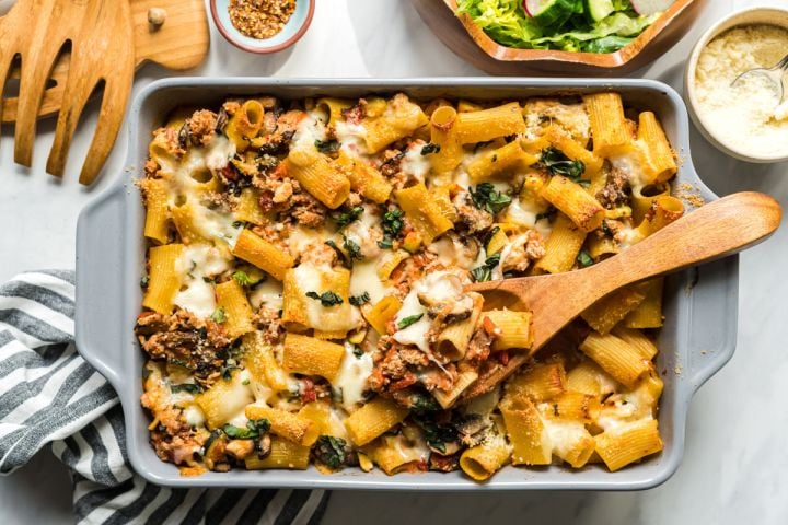 Baked Ziti Bolognese Baked ziti with ground beef, tomatoes, zucchini, and melted cheese in a baking dish.