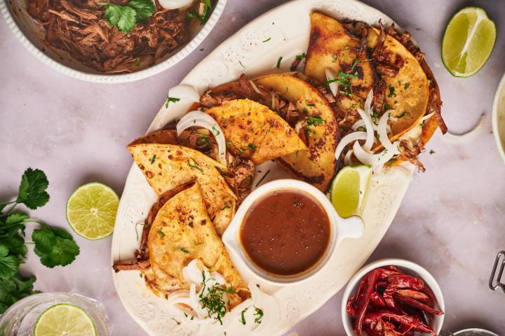 Birria Tacos Beef birria tacos in cripsy corn tortillas with melted cheese, cilantro, onion, and limes.