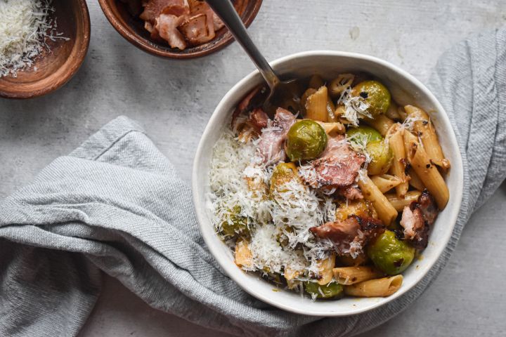 Brussels Sprouts Pasta with Bacon Brussels sprout pasta with bacon and Parmesan cheese in a bowl with a spoon.