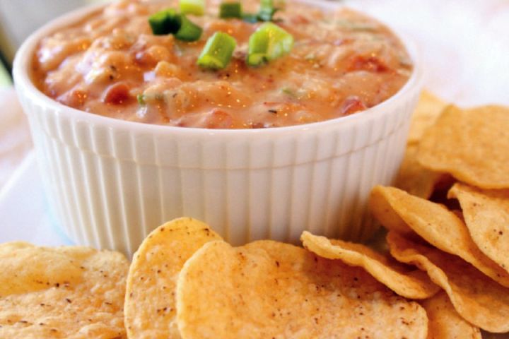 Healthy Chili Con Queso Chili con queso in a bowl with melted cheese, chilies, green onions, and tortilla chips.