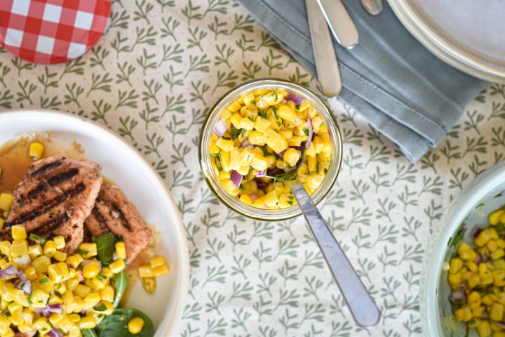 Corn Salsa Corn salsa in a jar with cilantro, red onion, poblano peppers, and lime juice.