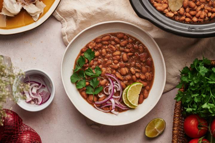 Crockpot Pinto Beans (No Soaking!) Crockpot pinto beans in a bowl with red onions, cilantro, and lime slices.