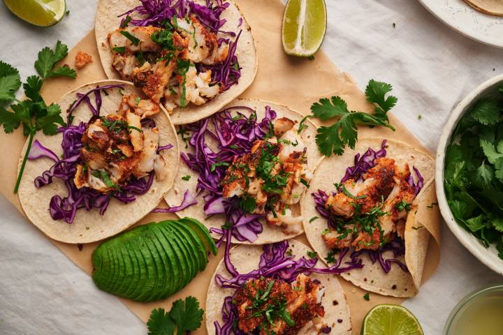 Fish Tacos Fish tacos with flaky seasoned fish served in a corn tortilla with cilantro, shredded red cabbage, and limes.