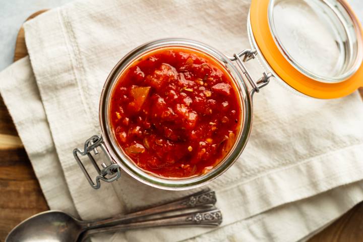 Fra Diavolo Sauce Fra diavolo sauce with tomatoes, chile flakes, garlic, onion, and spices in a glass jar.
