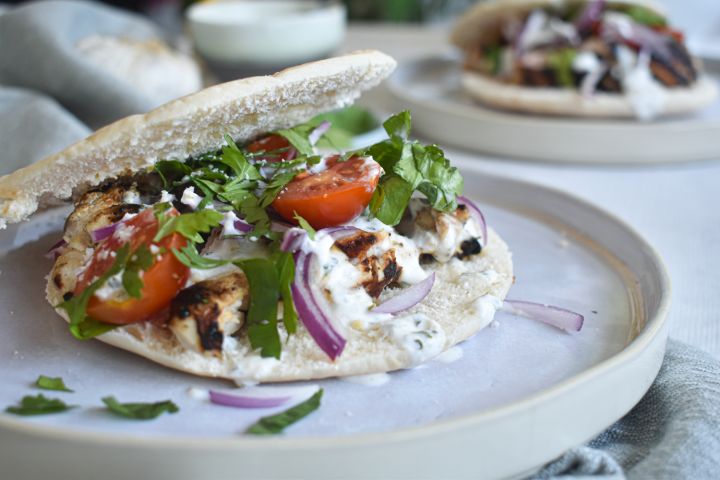 Grilled Chicken Souvlaki Grilled chicken souvlaki marinated in lemon and garlic served in a pita with tzatziki, tomatoes, red onions, and parsley.